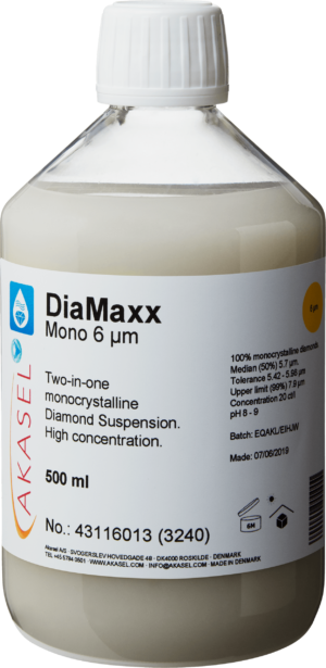 Akasel DiaMaxx Mono 6 µm: A 500 ml plastic bottle with a white screw cap, filled with a light, milky-white monocrystalline diamond suspension. The label shows the product name “DiaMaxx Mono 6 µm” along with the description “Two-in-one monocrystalline Diamond Suspension. High concentration.” Additional information includes: “100% monocrystalline diamonds,” “Median (50%) 5.7 µm,” “Tolerance 5.42 – 5.98 µm,” “Upper limit (99%) 7.9 µm,” and a concentration of “20 ct/l.” Symbols on the label provide instructions on storage and shelf life.