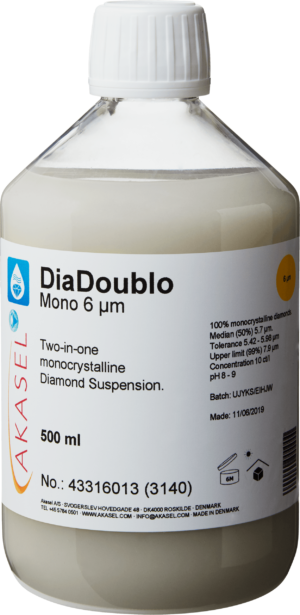Akasel DiaDoublo Mono 6 µm: A 500 ml plastic bottle with a white screw cap, filled with a light, milky-white monocrystalline diamond suspension. The label shows the product name “DiaDoublo Mono 6 µm” along with the description “Two-in-one monocrystalline Diamond Suspension.” Additional information includes: “100% monocrystalline diamonds,” “Median (50%) 5.7 µm,” “Tolerance 5.42 – 5.98 µm,” “Upper limit (99%) 7.9 µm,” and a concentration of “10 ct/l.” Symbols on the label provide instructions on storage and shelf life.