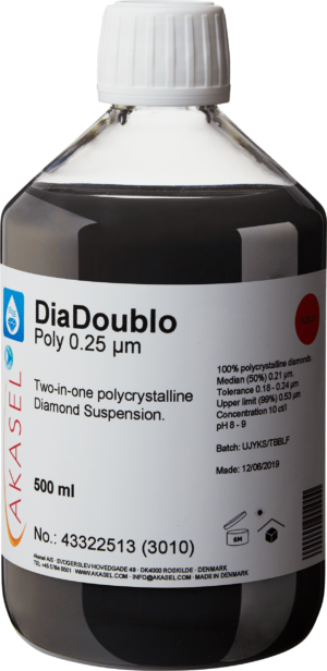 Akasel DiaDoublo Poly 0.25 µm: A 500 ml plastic bottle with a white screw cap, filled with a black liquid. The label shows the product name “DiaDoublo Poly 0.25 µm” and describes it as a “Two-in-one polycrystalline Diamond Suspension.” Additional information includes: “100% polycrystalline diamonds,” “Median (50%) 0.21 µm,” “Tolerance 0.18 – 0.24 µm,” “Upper limit (99%) 0.53 µm,” a diamond concentration of 10 ct/l, and a pH value of 8 – 9. A batch number field and production date are also provided on the label.