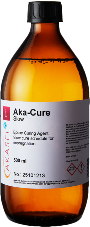 Akasel Aka-Cure Slow: A brown glass bottle with a yellow screw cap. The label features the Akasel logo, the product name "Aka-Cure Slow," and "Epoxy Curing Agent." Additional details include "Slow cure schedule for impregnation," a volume of "500 ml," and specific mixing instructions. Safety and application guidelines, along with precautionary symbols, are also included on the label. The bottle holds a clear liquid, specially developed for metallographic applications, perfect for preparing heat-sensitive samples and impregnation.
